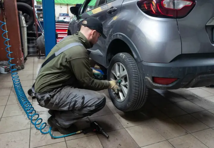Mechanik wymienia koło w samochodzie. Czy w Polsce obowiązują opony zimowe? To pytanie zadaje sobie wielu kierowców przed sezonem.