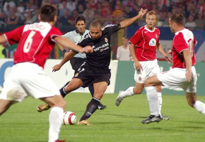 Piłkarz w czarnej koszulce Realu Madryt, gdzie grał Ronaldo, strzela gola.