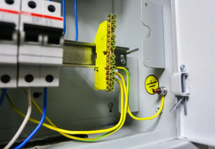 Instalacja elektryczna z wyłącznikami i listwą zaciskową. Pokazuje, jak zrobić uziemienie szpilkowe, łącząc przewody z listwą i obudową.