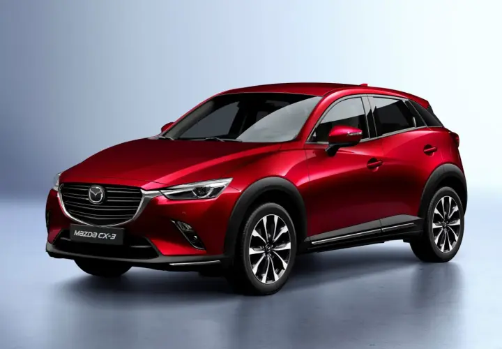 Czerwona Mazda CX-3 na tle jasnoszarego tła. Stylowy crossover, który zbiera pozytywne mazda cx-3 opinie.