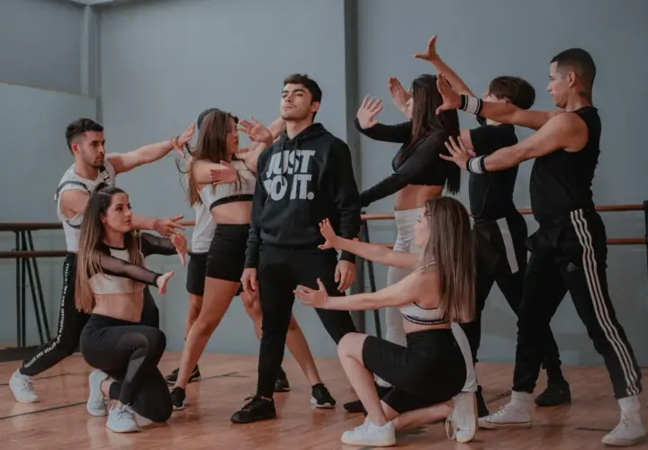 Un gruppo di giovani ballerini in abiti sportivi esegue una coreografia di danza pop in uno studio.