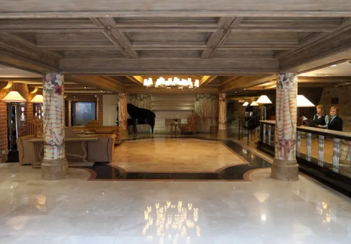 Eleganckie lobby hotelowe z fortepianem, recepcją i dwoma pracownikami.