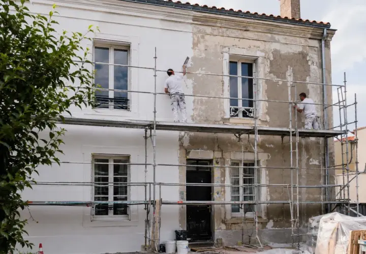 Ravalement de façade en cours, transformant une vieille bâtisse pour une plus-value certaine. Les ouvriers travaillent sur des échafaudages.