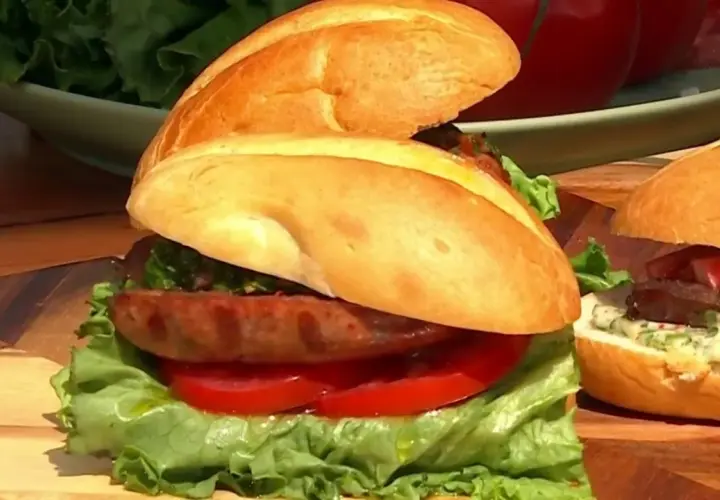 Sandwich de salchicha con lechuga, tomate y salsa chimichurri, con sus ingredientes frescos listos para servir.