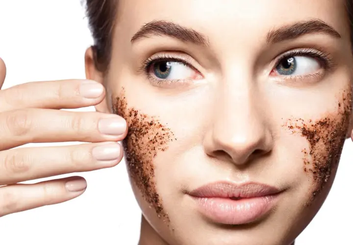 Une femme applique un gommage visage à base de grains de café. Elle montre comment faire un gommage visage pour une peau douce.