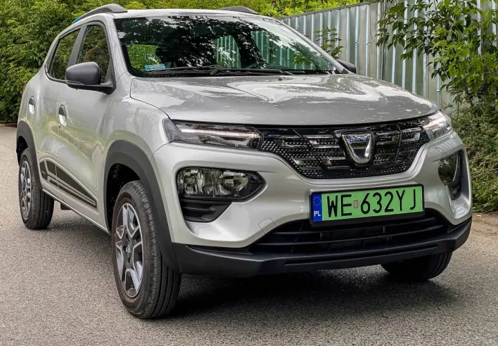 Srebrna Dacia Spring z zieloną tablicą rejestracyjną. Ten elektryczny samochód oferuje dobry zasięg na jednym ładowaniu.