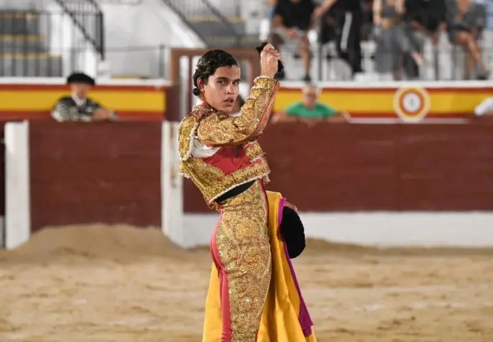 Joao Ferreira, banderillero, con traje de luces dorado y rojo, sostiene un capote en la plaza de toros.