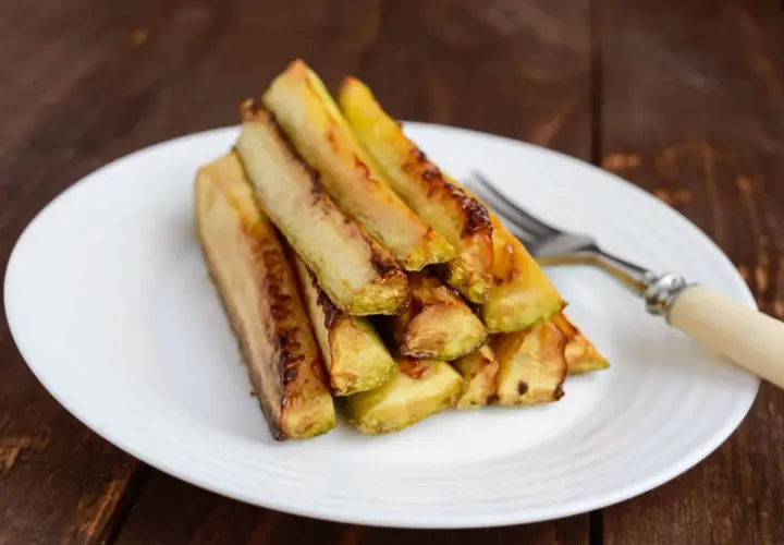 Zucchine in carpione dorate e succulente, impilate su un piatto bianco, pronte per essere gustate.