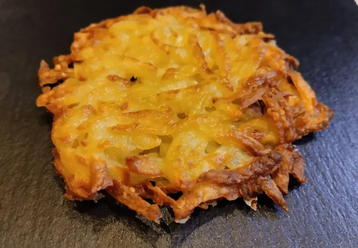 Un croccante rosti di patate dorato, preparato con patate grattugiate e cotto fino a ottenere una deliziosa crosticina.