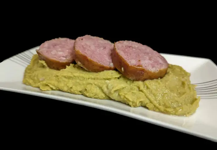 Trois tranches de saucisse sur une purée de pois cassés, un plat réconfortant.