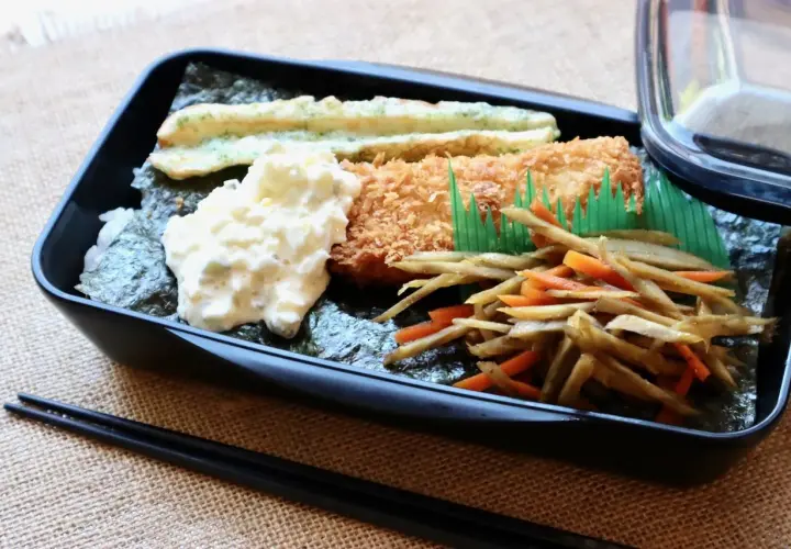 A delicious nori bento box with fried fish, creamy potato salad, and stir-fried vegetables.