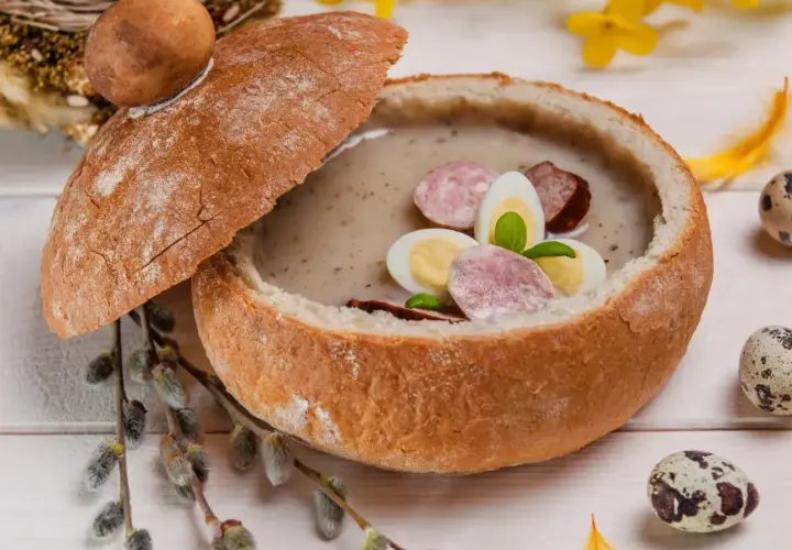 Zupa biały barszcz w chlebie, ozdobiona jajkiem i kiełbasą. Idealna, gdy zastanawiasz się, jak odkwasić zupę.