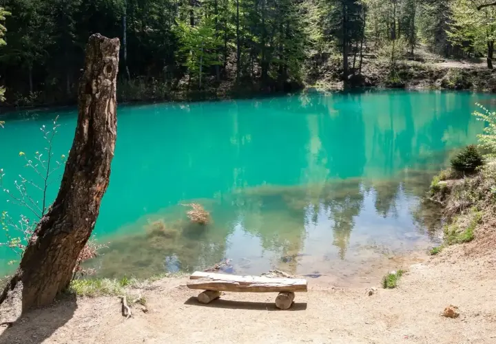 Turkusowe jezioro w Beskidach, idealne na weekendowe atrakcje. Ławka zaprasza do odpoczynku nad wodą.
