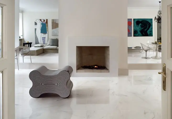 Pavimento rettificato: pro e contro. Un salotto moderno con camino, opere d'arte e un particolare divano a forma di osso.