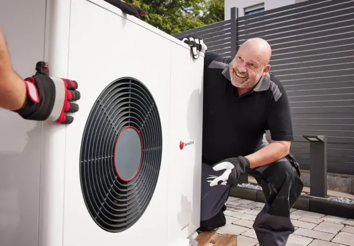 Un technicien souriant aide à installer une pompe à chaleur air air, un système efficace pour le confort de votre maison.
