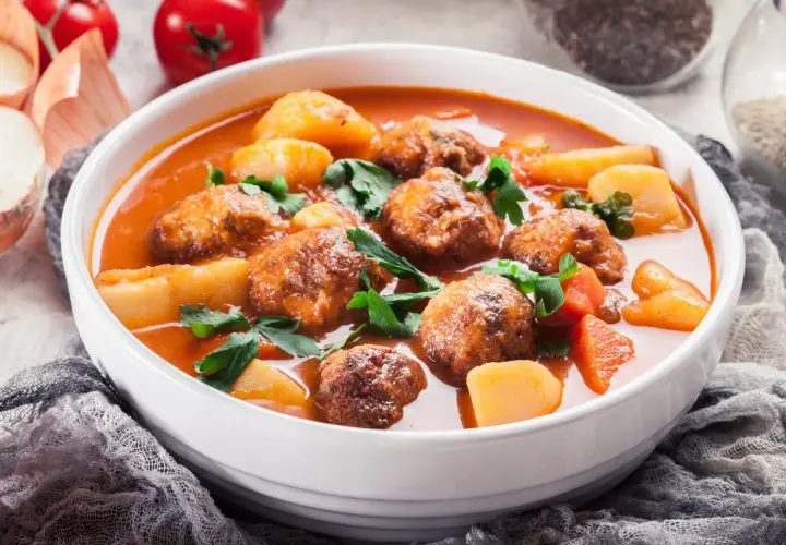 Zupa klopsowa babci: aromatyczne klopsiki w pomidorowym sosie z ziemniakami i natką pietruszki.