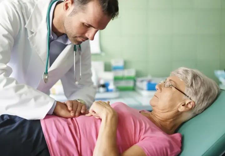 Lekarz bada pacjentkę, która skarży się na przelewanie w brzuchu. Delikatnie dotyka jej brzucha, próbując zdiagnozować przyczynę dolegliwości.