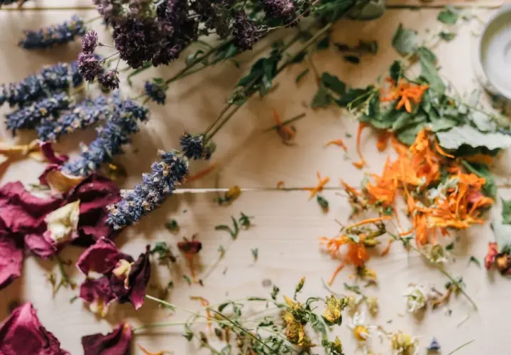 Comment faire sécher des fleurs avec de la laque : roses, lavande, et fleurs oranges séchées sur fond de bois.