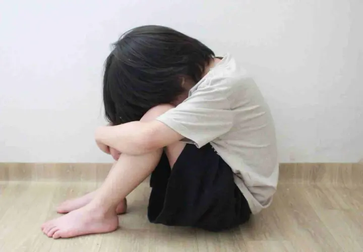 Bambino rannicchiato, un'immagine che evoca la necessità di capire come aiutare un figlio depresso.