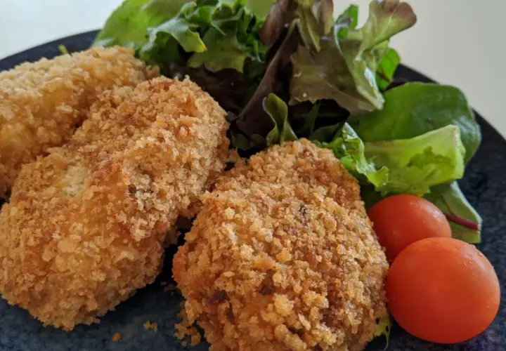 Golden potato croquettes served with fresh salad and cherry tomatoes.