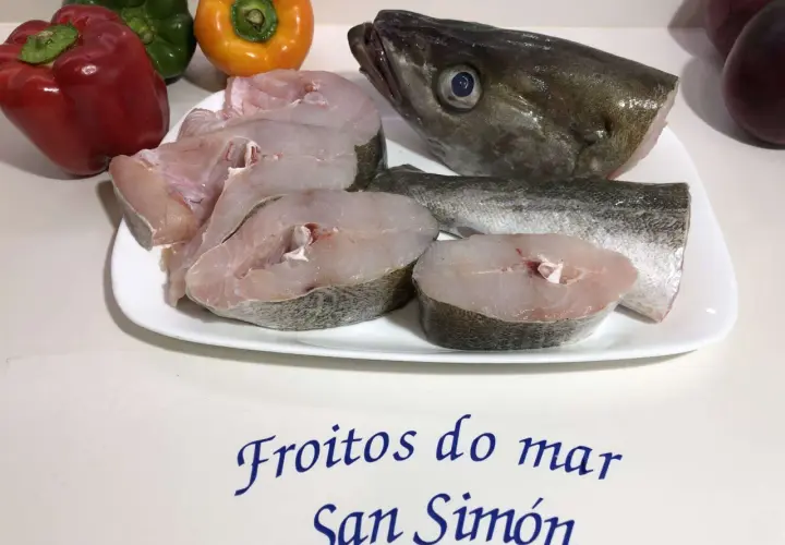 Rodajas de abadejo pescado fresco en plato blanco, junto a pimientos y el texto "Froitios do mar San Simón".