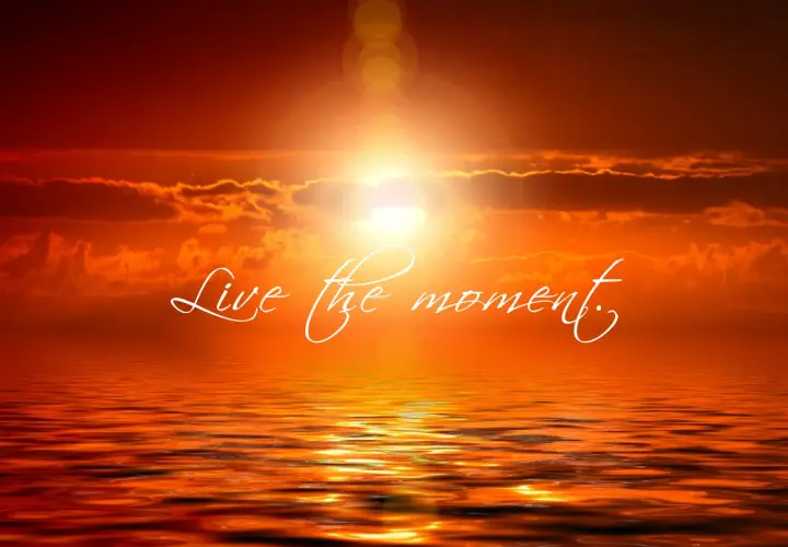 Tramonto infuocato sull'oceano, con la scritta "Live the moment" che invita a vivere il presente.
