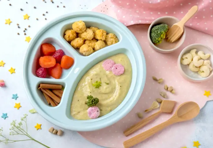 Kolorowy talerzyk z jedzeniem dla malucha: puree z warzyw, marchewka, maliny, chrupki i brokuł. Idealny na blw pierwszy posiłek.