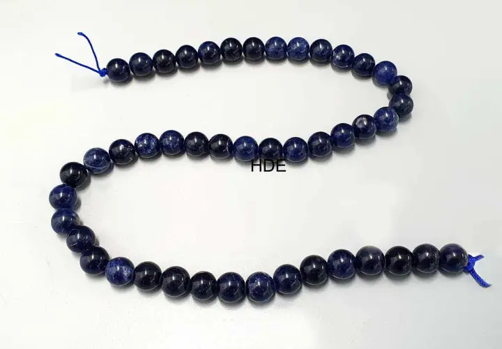 Eine Kette aus tiefblauen Sodalith-Perlen, die auf einem weißen Hintergrund liegen.