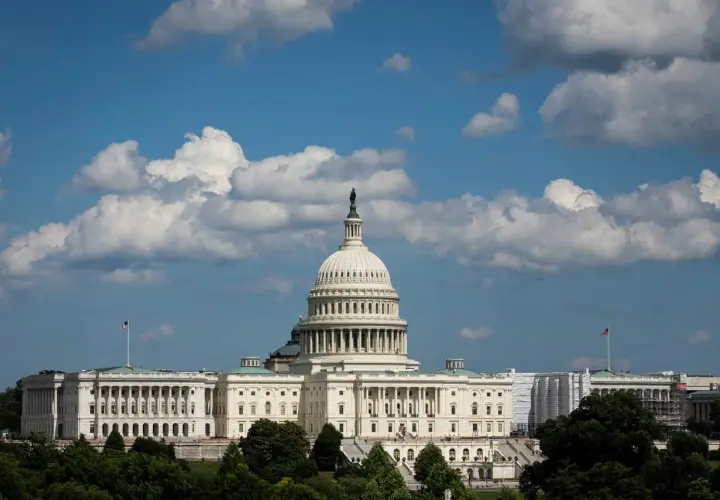 The U.S. Capitol building under a cloudy sky. Members of Congress work within these walls, but do members of Congress have security clearances?