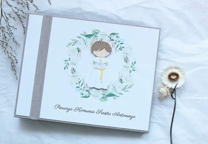 Album na pamiątkę Pierwszej Komunii Świętej dla chłopca. Urocza ozdoba z postacią dziecka w wianku. Idealny pomysł na prezent.