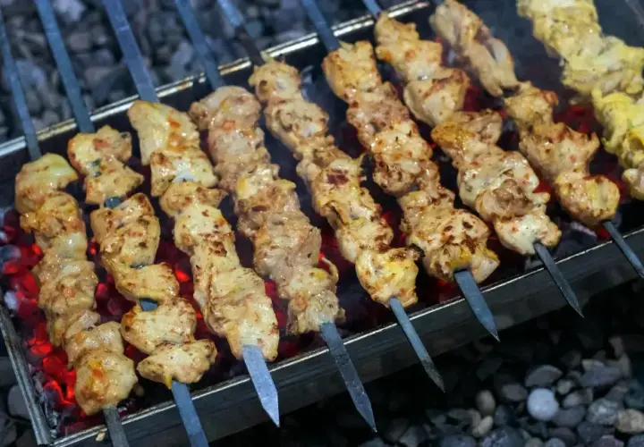 Kebab z mięsa mielonego na patyczkach grilluje się nad żarem. Mięso jest soczyste i apetyczne.