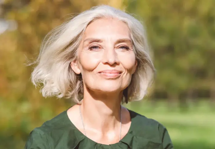 Mujer sonriente con cabello rubio platino, ideal para matizar canas. Su piel irradia luz natural.
