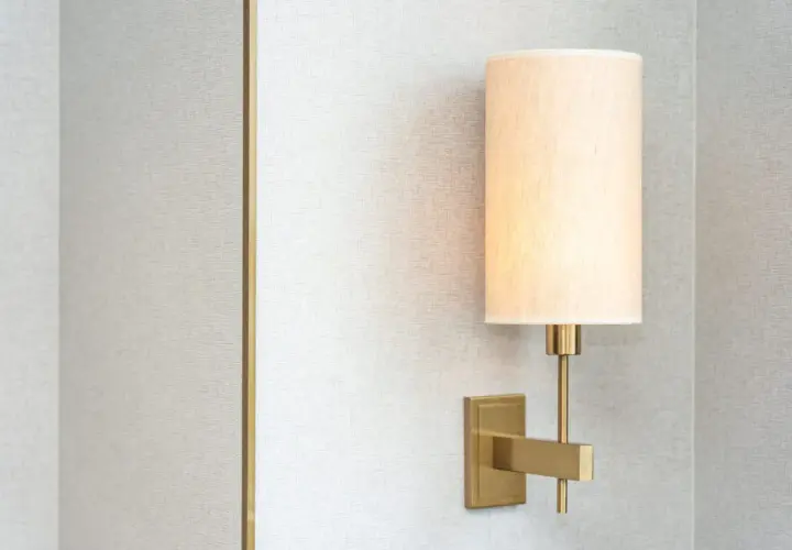 Aplique de pared moderno con pantalla de tela beige, montado en una pared con textura gris.