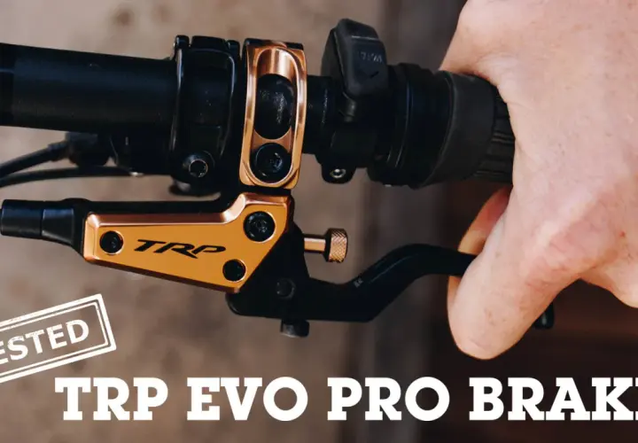 A hand squeezes a black brake lever on a bicycle handlebar. The gold TRP EVO PRO BRAKES are featured in this review.