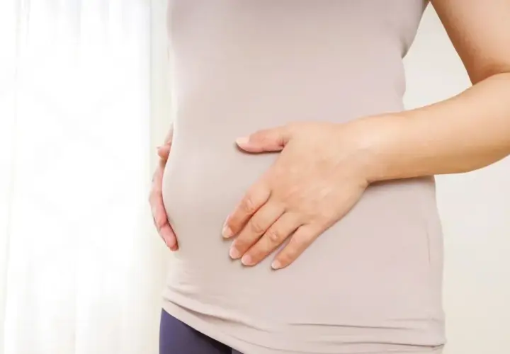 Mujer tocando su abdomen, buscando soluciones para quitar barriga menopausia.