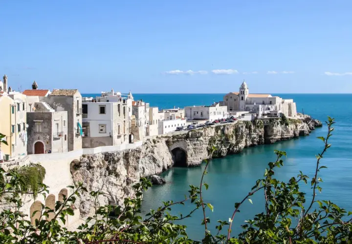 A picturesque coastal town in southern Italy, perfect for a southern Italy itinerary. White buildings cling to cliffs overlooking the turquoise sea.