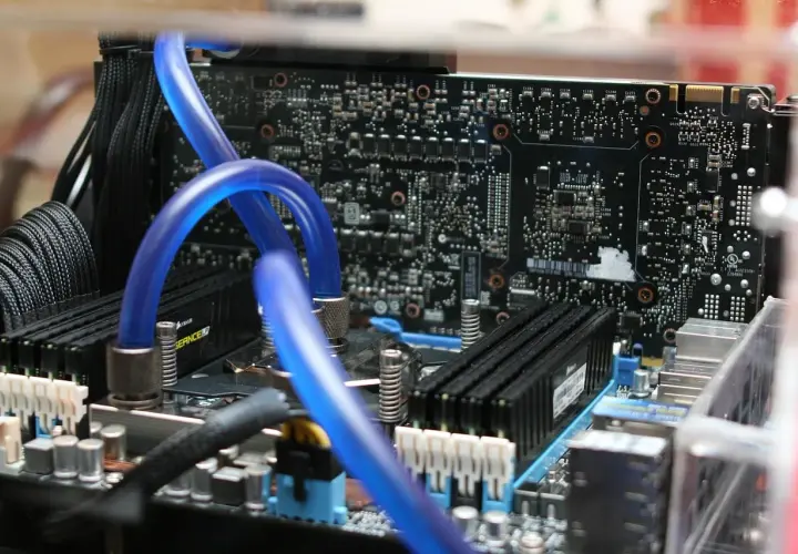 Composants d'un PC, dont des tubes bleus de watercooling et des barrettes de RAM. Utile pour connaître sa carte mère Windows 10.