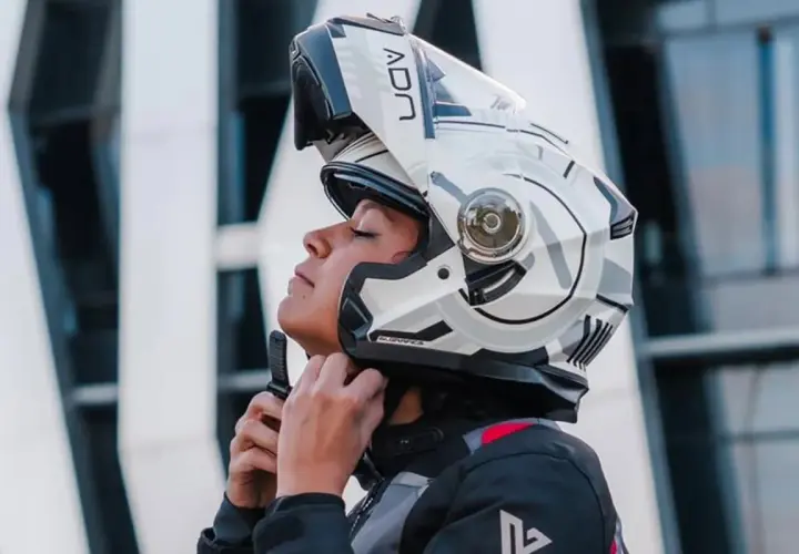 Mujer ajustando su casco integral o modular, listo para la aventura.