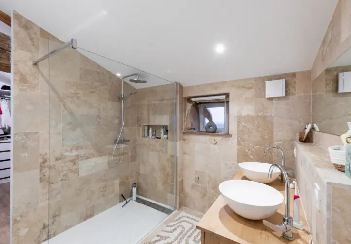 Salle de bain moderne aux tons sable, avec douche à l'italienne, double vasque et dressing attenant. Un exemple de travaux rénovation salle de bain réussis.