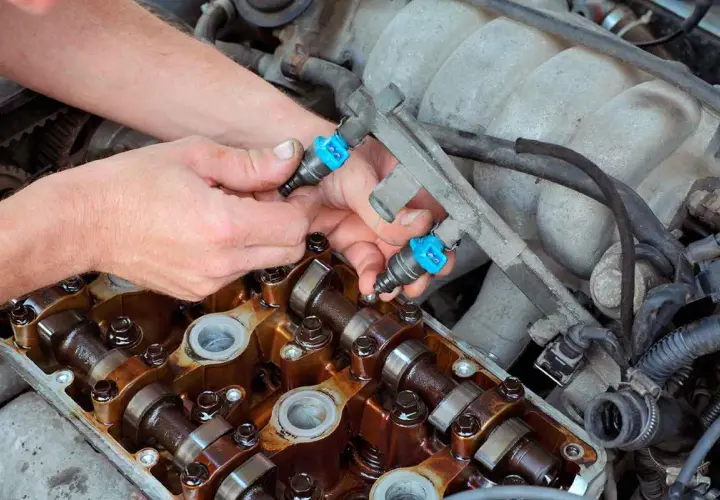 Mecánico instala inyectores de combustible en un motor. Aunque se puede circular con un inyector averiado, es mejor repararlo.