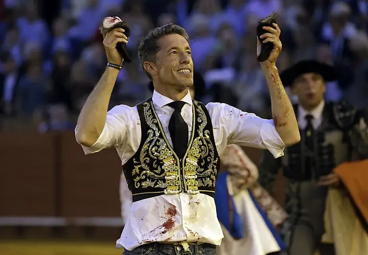 Manuel Escribano, triunfador, levanta las orejas del toro en la plaza.