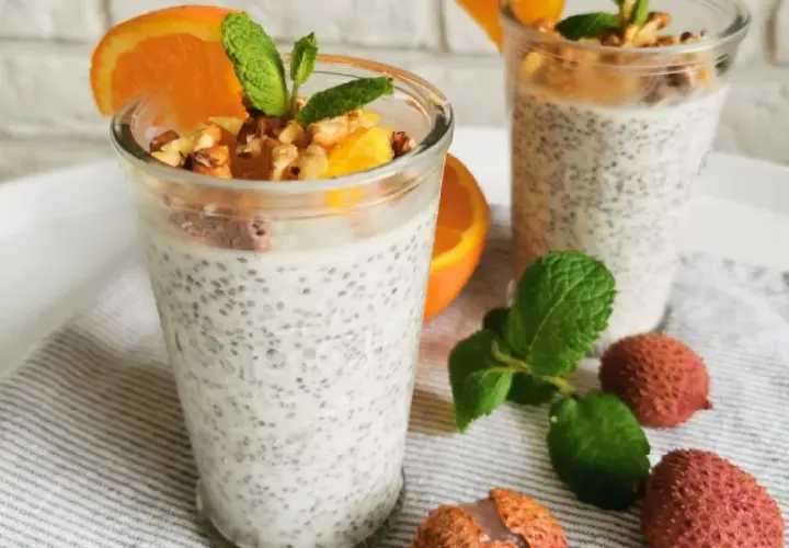 Pudding chia z pomarańczą i orzechami, ozdobiony miętą i owocami lychee.