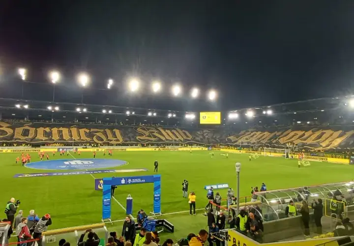 Piłkarze GKS Katowice i Górnika Zabrze na murawie. Na trybunach ogromna oprawa z napisem "Górniczy Klub".