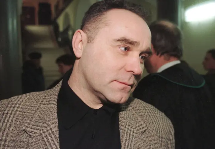 Mężczyzna w tweedowej marynarce, jak zostałem gangsterem o kim, w tle prawnik w todze.
