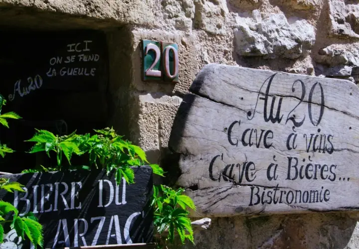 Bonjour! Drewniany szyld "Au 20" zaprasza do piwnicy z winami i piwami. Obok tablica z napisem "Biere du Arzac".