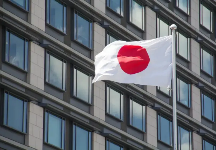 Flaga Japonii powiewa przed nowoczesnym budynkiem. Japonia liczba ludności to ponad 125 milionów osób.