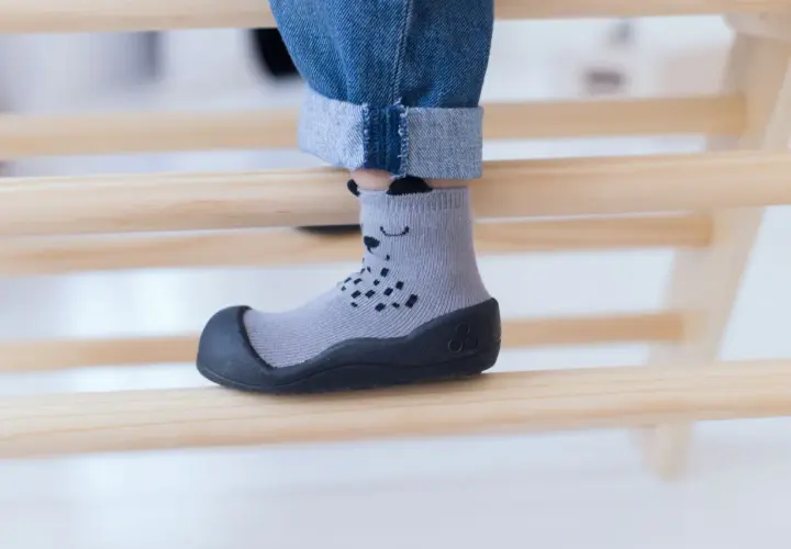 Szare skarpeto-buty z misiem, idealne dla dziecka z wysokim podbiciem, zapewniające komfort i bezpieczeństwo podczas zabawy.