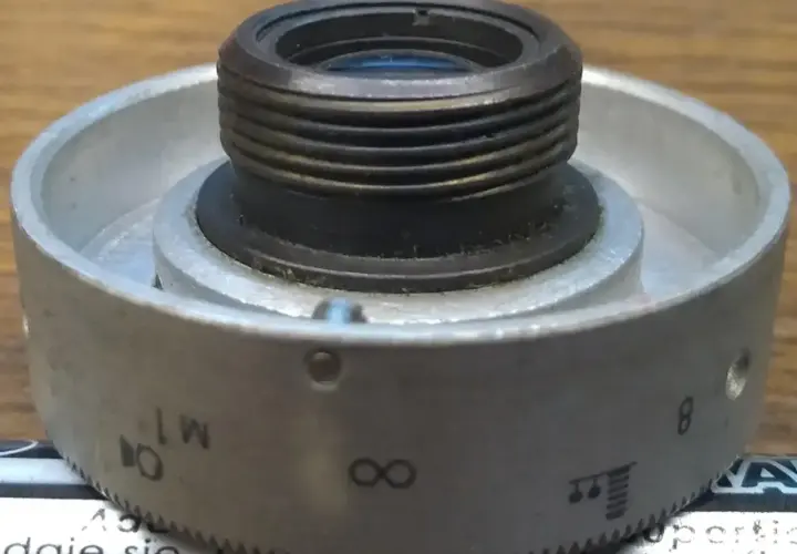 Metalowy pierścień z oznaczeniami od 1 do 8, nieskończoności i innymi symbolami, służący do regulacji obiektywu. Idealny do zoom test.