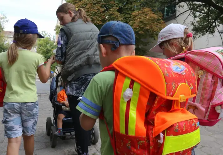 Dzieci z plecakami, gotowe do szkoły. W tle wózek z dzieckiem. Ponad 300 wniosków elektronicznych czeka na rozpatrzenie.