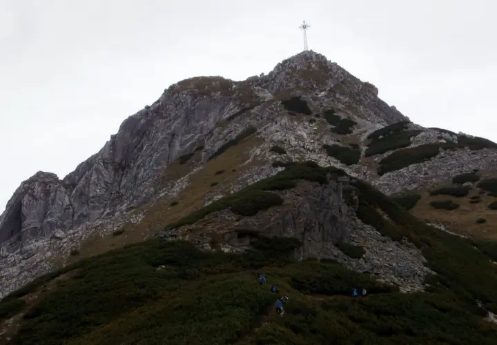 Wspinaczka na Giewont, gdzie w trudnym terenie pomagają łańcuchy. Widok na szczyt z krzyżem.